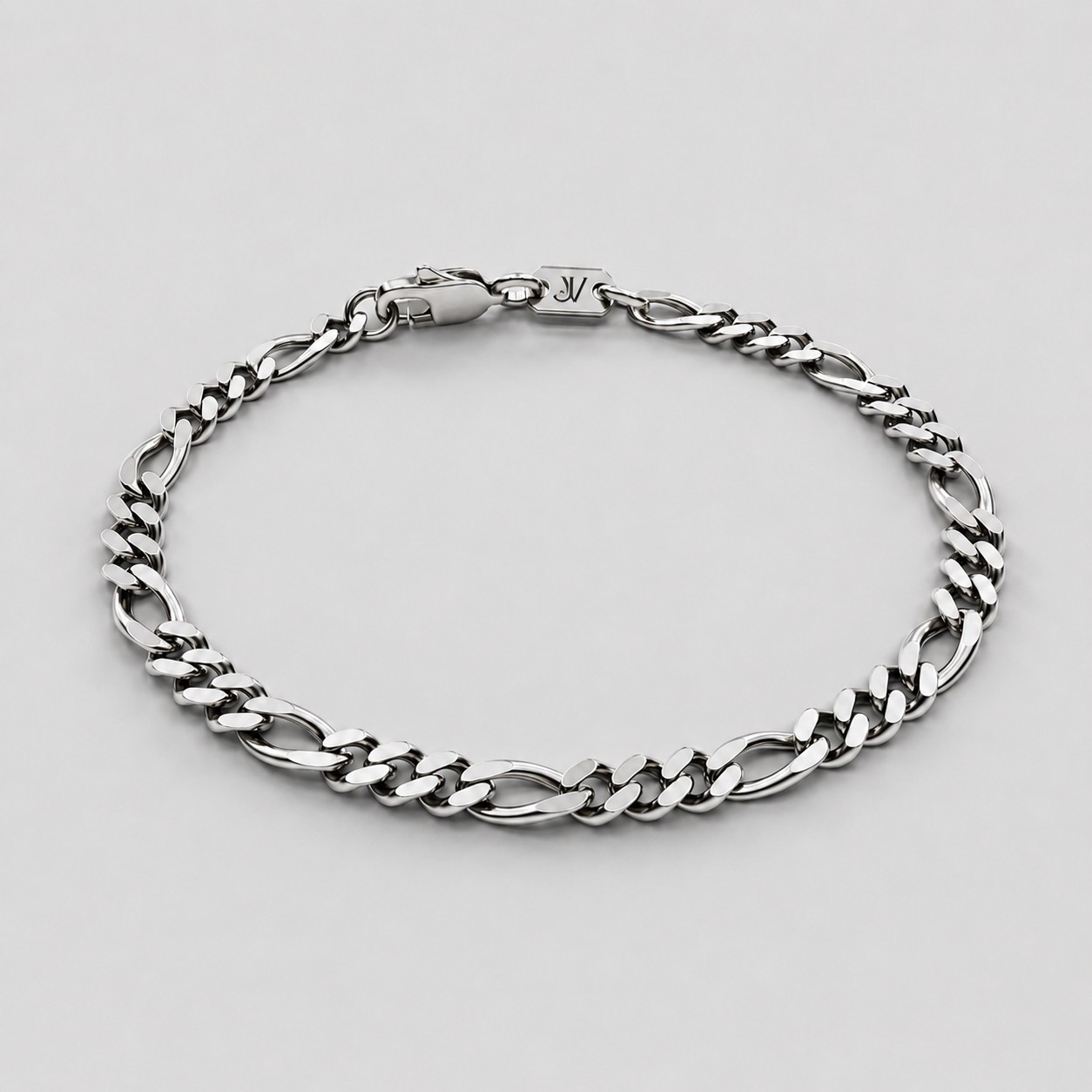 Composição plana da pulseira de corrente fígaro prateada de 5 mm com fecho mosquetão e placa, fundo branco, JVillion
