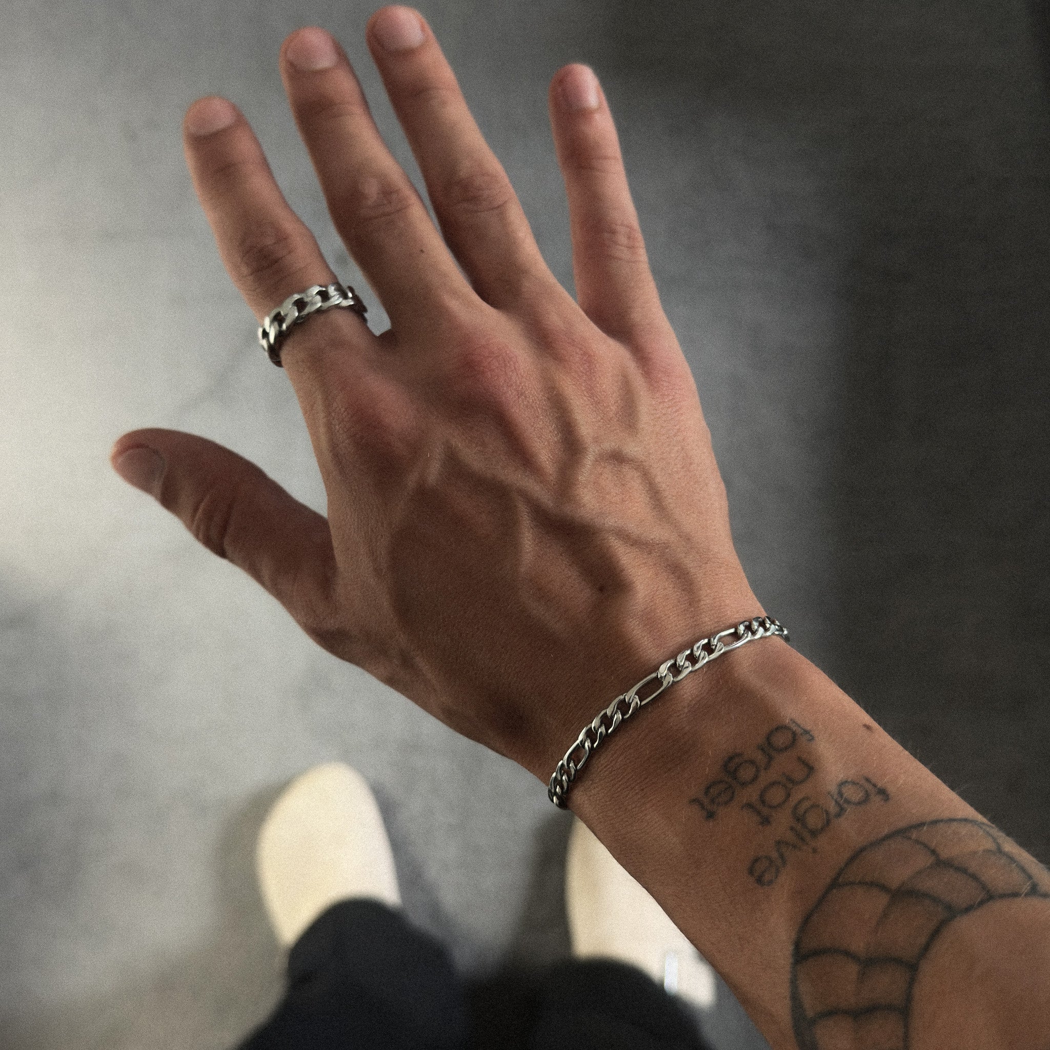 Pulseira de corrente fígaro prateada de 5 mm e anel de corrente na mão de um modelo, vista de cima, JVillion