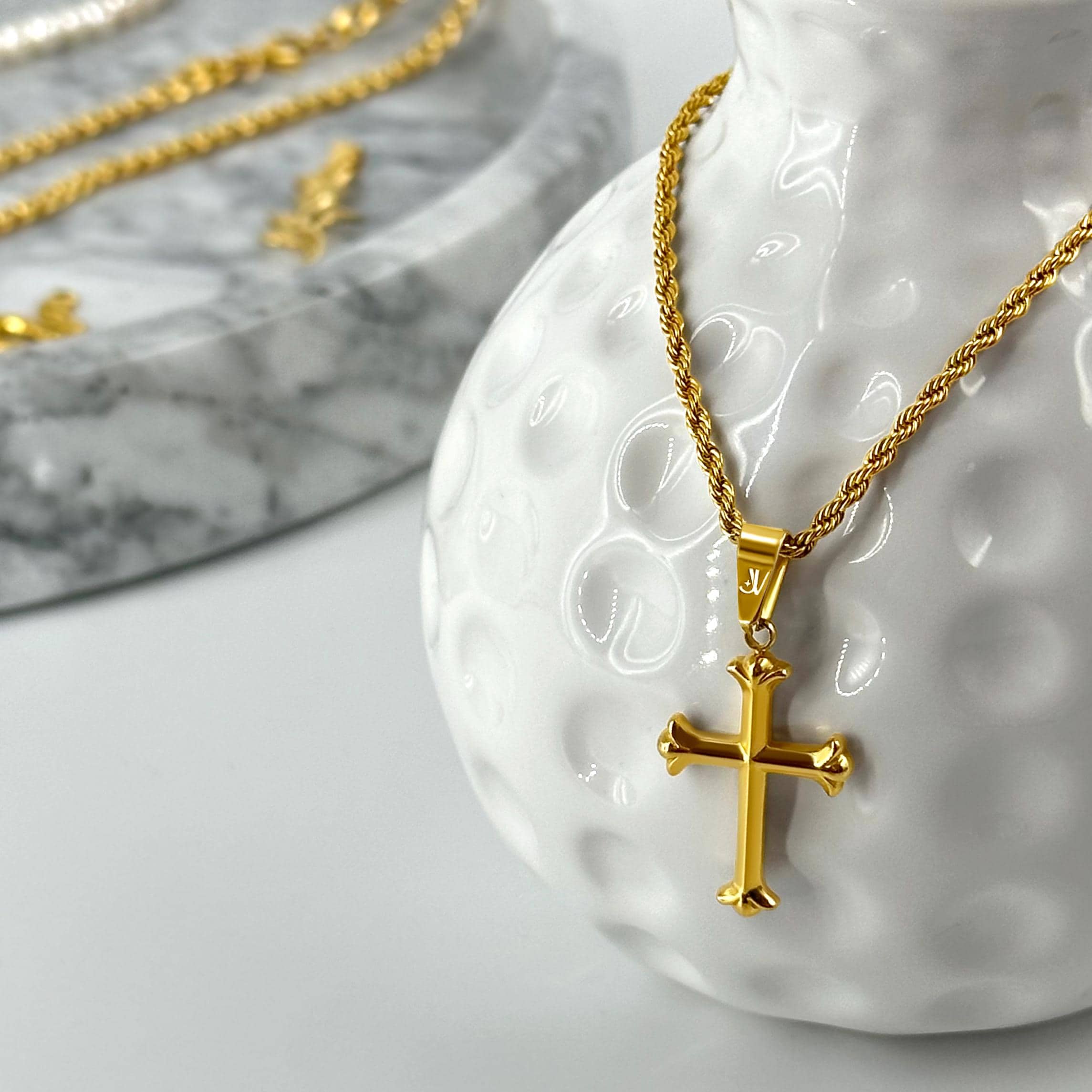 Gold cross pendant on 2mm rope chain, styled product scene, JVillion