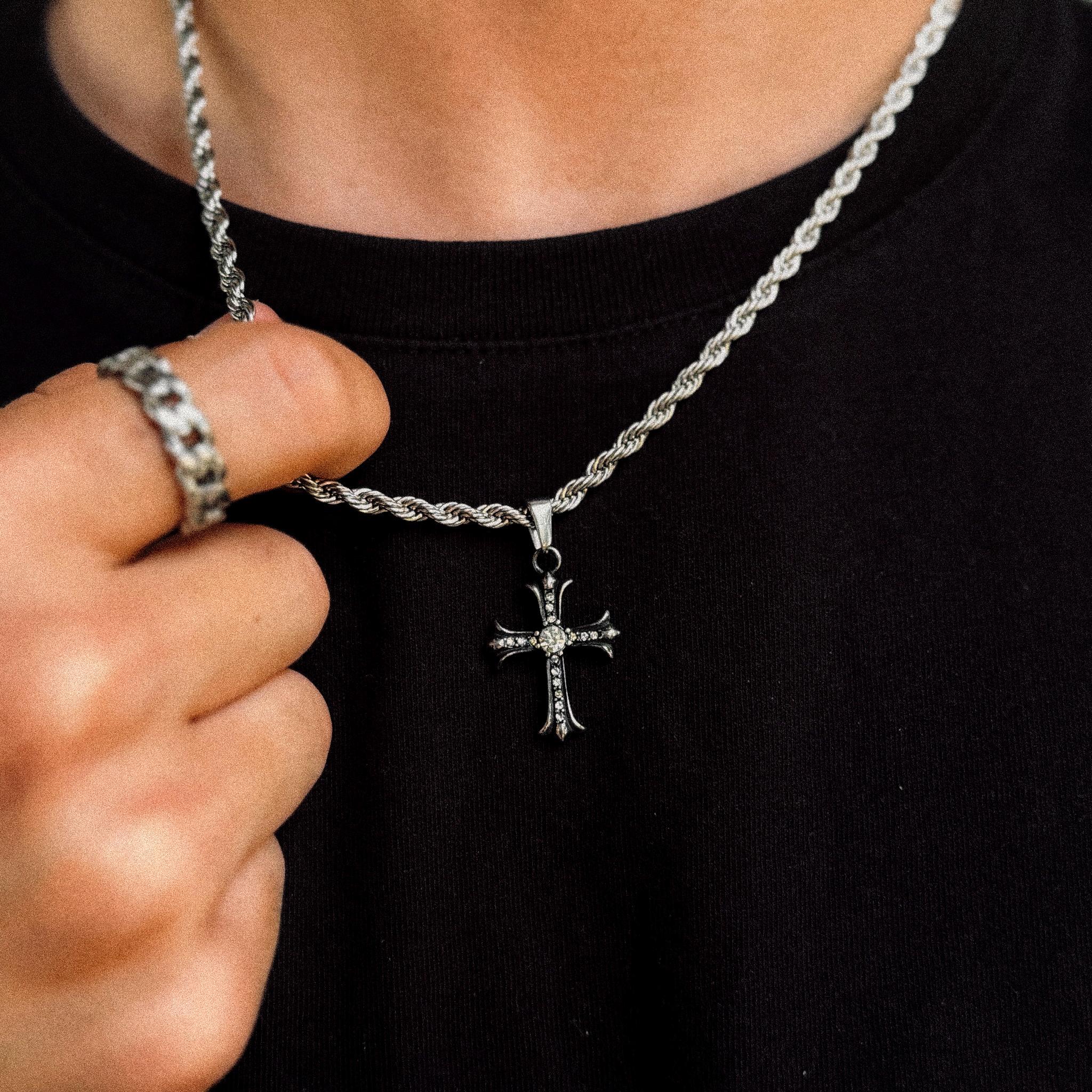 Shiny silver cross pendant on 4mm rope chain held to camera, JVillion